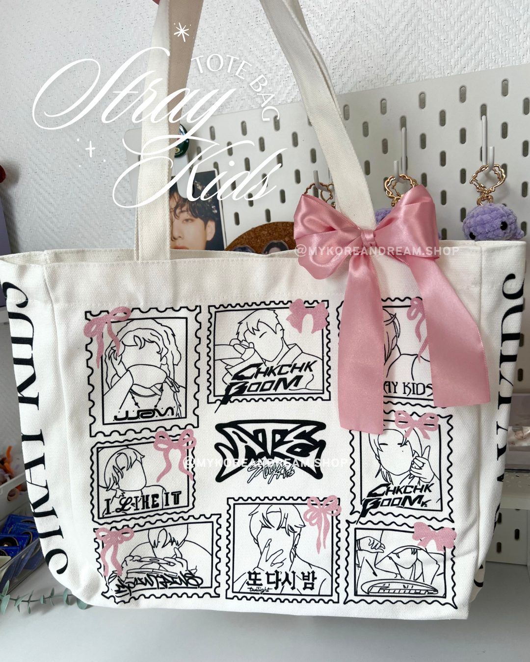 Grand tote bag en coton beige avec un design inspiré de Stray Kids, composé d’illustrations minimalistes encadrées comme des timbres. Un nœud en satin rose est attaché à l’anse.