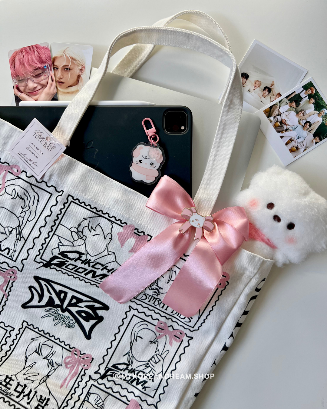 Tote bag rempli d’accessoires K-pop, placé sur une étagère avec des porte-clés et des goodies en arrière-plan.