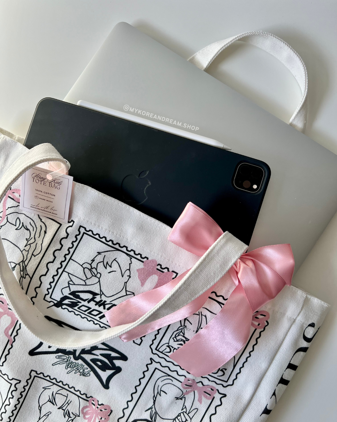 Gros plan sur le tote bag montrant sa capacité à contenir un ordinateur portable et d’autres objets du quotidien. Le tissu en coton et les détails du design sont visibles.